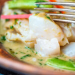 Close up Thai green fish curry showing big flakes of perfectly cooked cod featuring a title overlay.