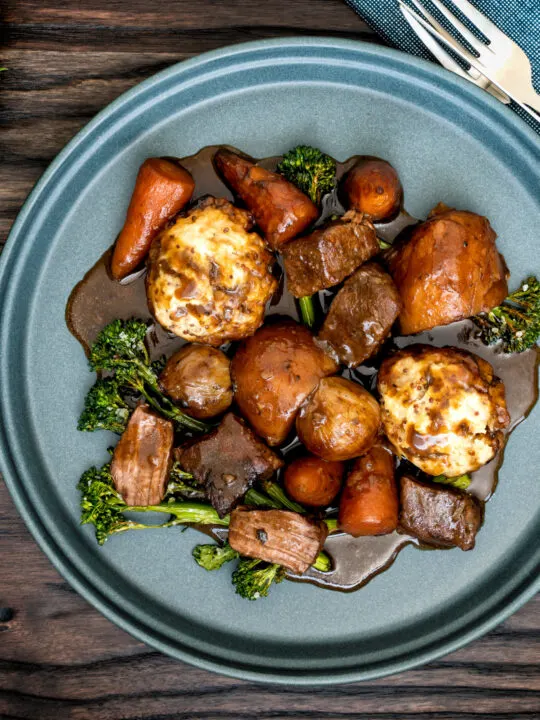 Overhead British beef and ale stew with dumplings, carrots and potatoes.