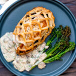 Overhead Chicken en croute with a mushroom cream sauce and roasted tenderstem broccoli featuring a title overlay.
