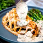 Mushroom sauce being poured over chicken en Croute.