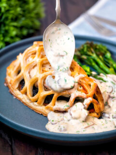 Mushroom sauce being poured over chicken en Croute.