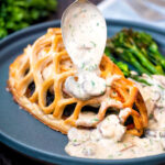 Mushroom sauce being poured over chicken en Croute featuring a title overlay.