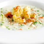 Chunky creamy cauliflower soup with a paprika garnish.