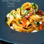 Harissa pasta with with feta cheese and roasted peppers in a black bowl featuring a title overlay.