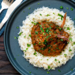 Overhead Indian inspired lamb chop curry served with rice featuring a title overlay.