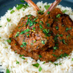 Close up Indian inspired lamb chop curry served with rice featuring a title overlay.