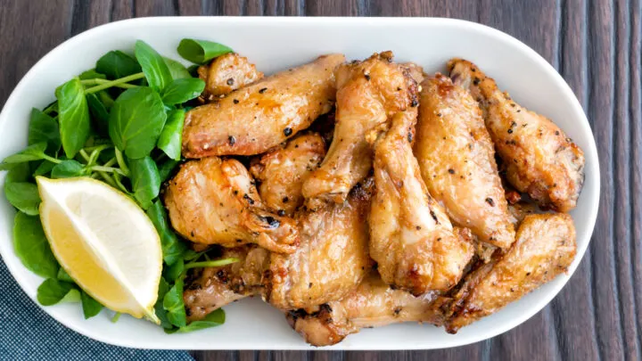 Crispy lemon pepper wings served with a green salad and lemon wedge.