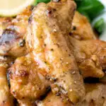 Close up crispy lemon pepper chicken wings served with a green salad.