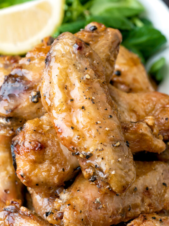 Close up crispy lemon pepper chicken wings served with a green salad.