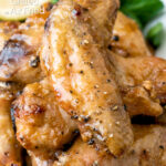 Close up crispy lemon pepper chicken wings served with a green salad featuring a title overlay.
