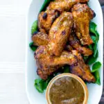 Overhead spicy mango habanero hot wings served with extra dipping sauce.