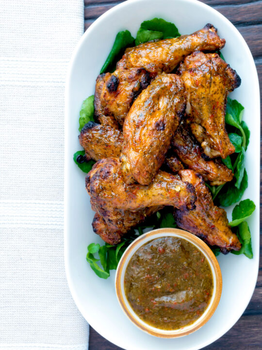 Overhead spicy mango habanero hot wings served with extra dipping sauce.