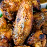 Close up spicy mango habanero hot wings served with extra dipping sauce.