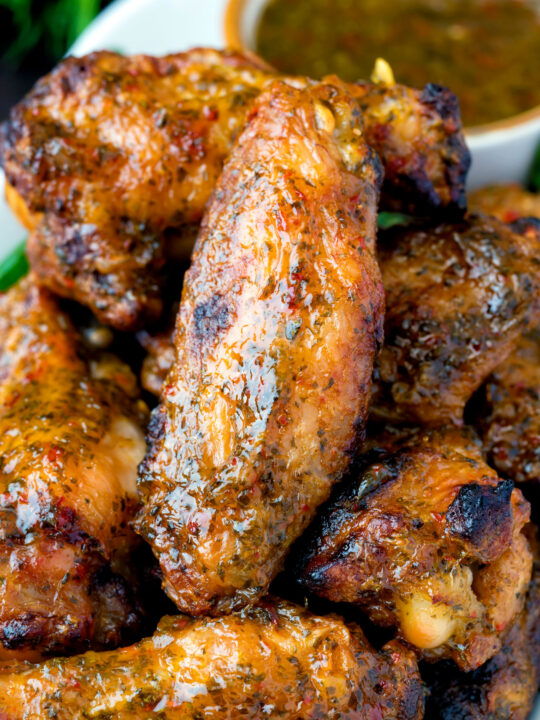 Close up spicy mango habanero hot wings served with extra dipping sauce.