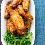 Overhead pineapple and jalapeno pepper glazed chicken wings served with rocket.