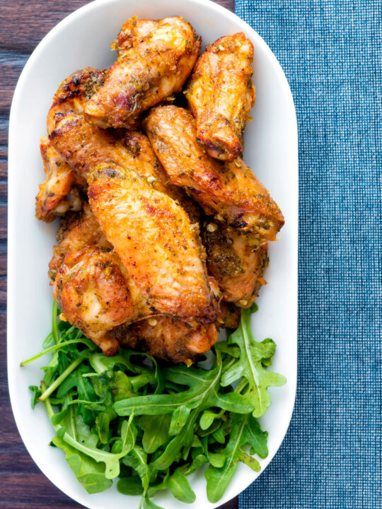 Overhead pineapple and jalapeno pepper glazed chicken wings served with rocket.