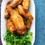 Overhead pineapple and jalapeno pepper glazed chicken wings served with rocket featuring a title overlay.