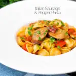 Sausage and pepper orecchiette pasta in a light tomato sauce with fresh parsley featuring a title overlay.