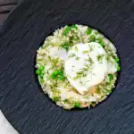 Overhead smoked haddock risotto with peas topped with a poached egg and fresh dill.