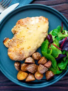 Overhead chicken parmo cheese topped breaded chicken escalope served with fried potatoes.