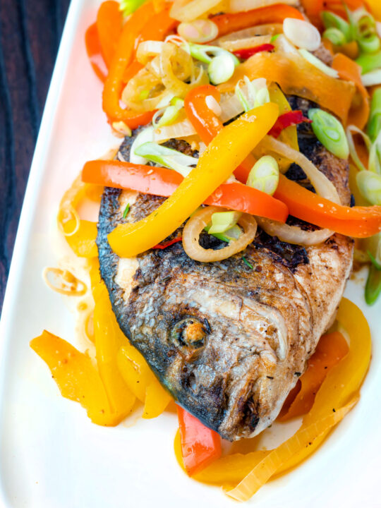 Close up Jamaican influenced escovitch fish with sea bream and "pickled" peppers and onions.