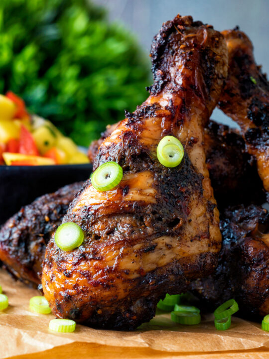 Close up Jamaican jerk chicken drumstick with green onions.