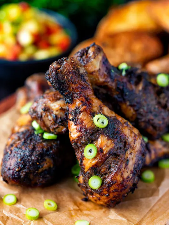 Jamaican jerk chicken drumsticks with green onions.