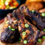 Jamaican jerk chicken drumsticks with green onions featuring a title overlay.