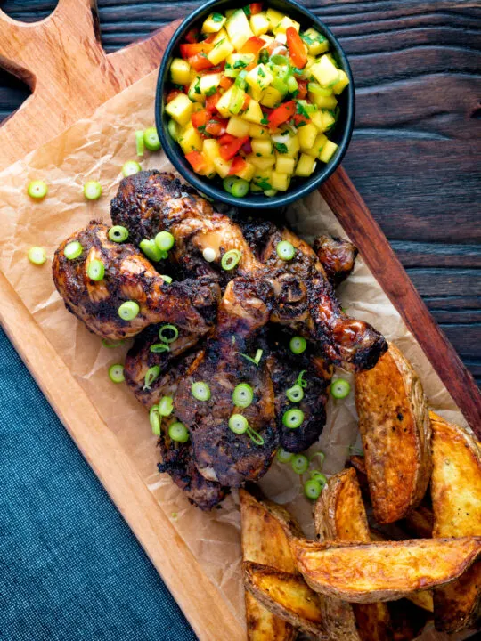 Overhead Jamaican jerk chicken drummers with potato wedges and mango salsa.