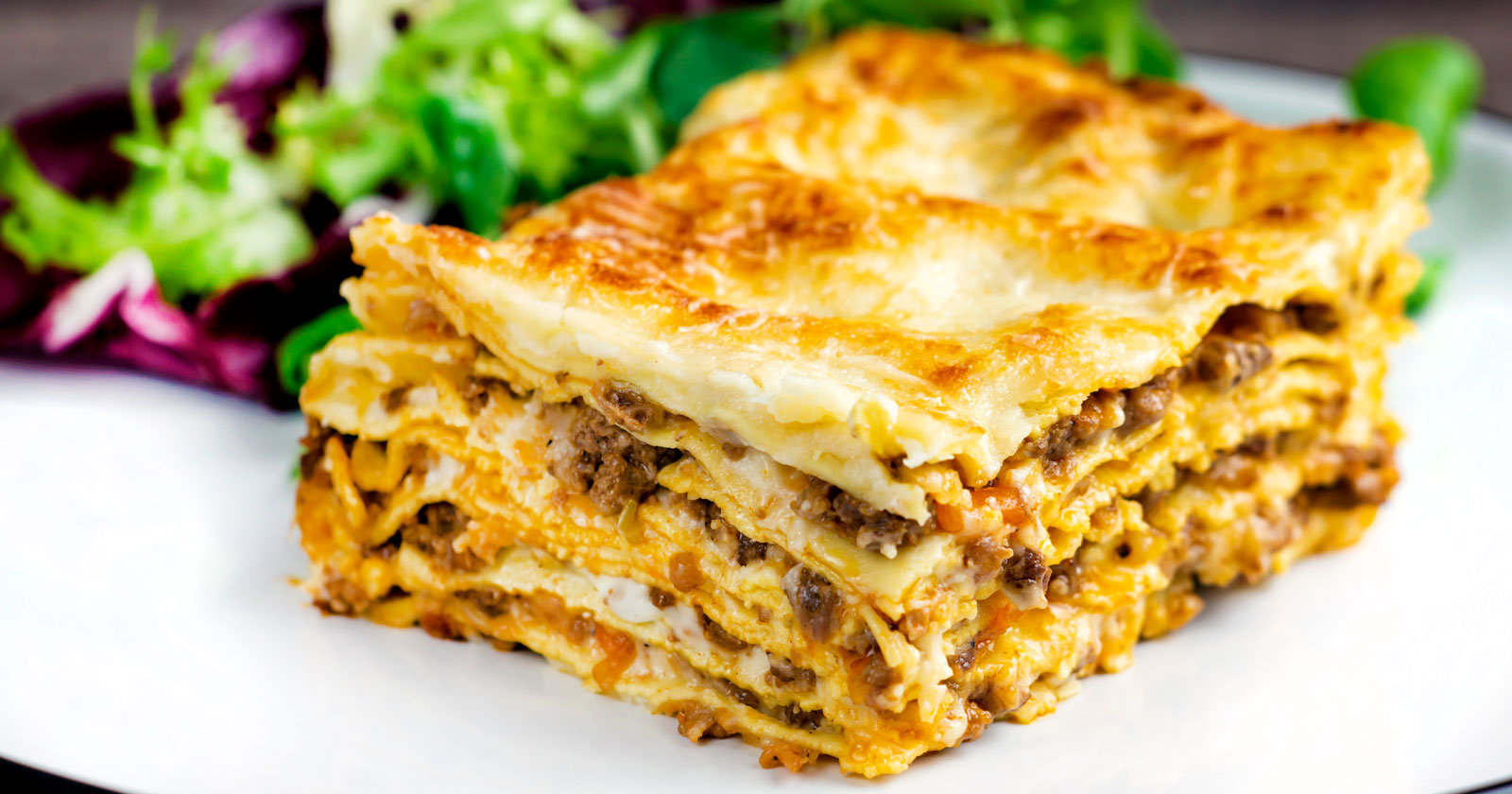 Perfectly layered lasagna bolognese with a crispy cheesy topping served with a side salad.