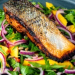 Pan fried jerk salmon fillet served with mango and rockets salad.