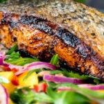 Close up pan fried jerk salmon fillet served with mango and rocket salad.