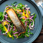 Overhead pan fried jerk salmon fillet served with mango and rocket salad.