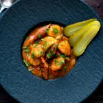 Overhead Hungarian paprikas krumpli or paprika potatoes stew with pickles.