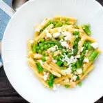 Overhead pea and asparagus pasta with casarecce, feta cheese and chilli flakes.