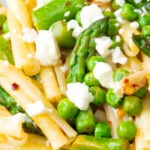 Close up pea and asparagus pasta with casarecce, feta cheese and chilli flakes.