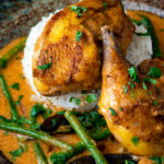 Close up pheasant curry with coconut milk, green beans and rice featuring a title overlay.