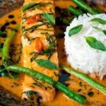 Close up red Thai salmon curry with green beans and jasmine rice.
