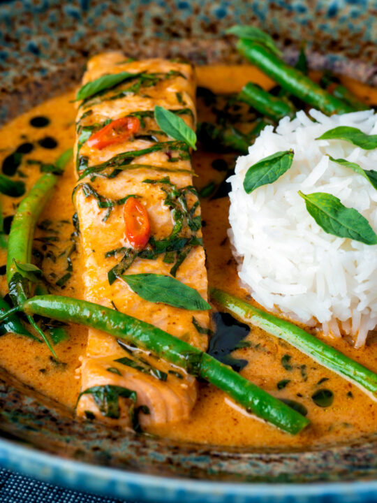 Close up red Thai salmon curry with green beans and jasmine rice.