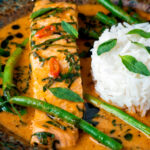 Close up red Thai salmon curry with green beans and jasmine rice featuring a title overlay.