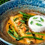 Red Thai salmon curry with green beans and jasmine rice featuring a title overlay.