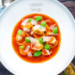Overhead store bought tortellini soup with tomato, fresh basil and parmesan shavings featuring a title overlay.