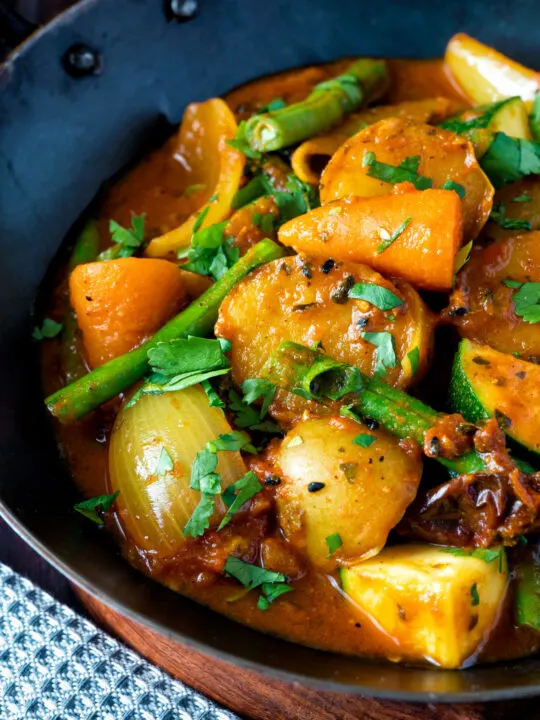 Close up vegan mixed vegetable karahi curry served in an iron kadai.