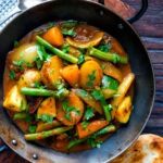 Overhead vegan mixed vegetable karahi curry served in an iron kadai.