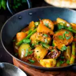 Vegan mixed vegetable karahi curry served in an iron kadai featuring a title overlay.