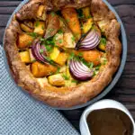 Overhead roasted vegetable toad in the hole with a jug of vegetarian onion gravy.