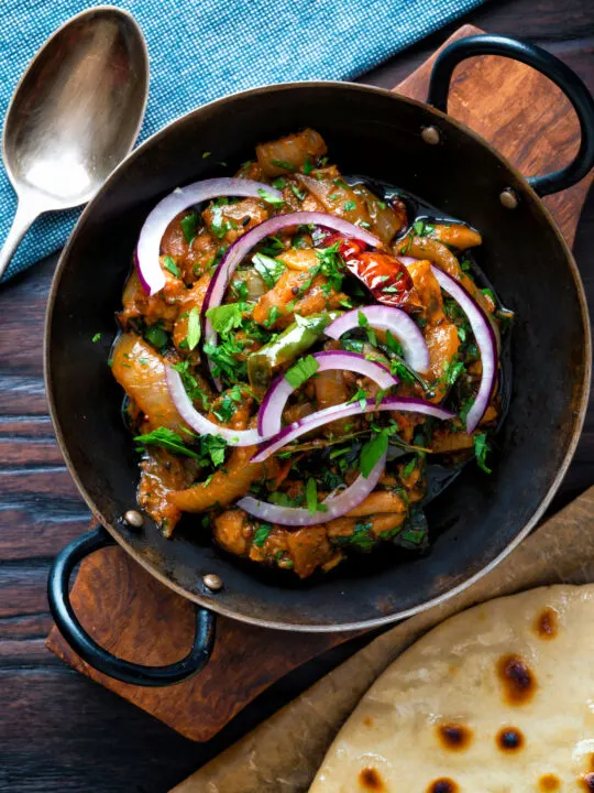 Overhead achari chicken or chicken pickle served in a kadai with a chapati.