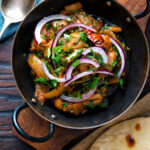 Overhead achari chicken or chicken pickle served in a kadai with a chapati featuring a title overlay.