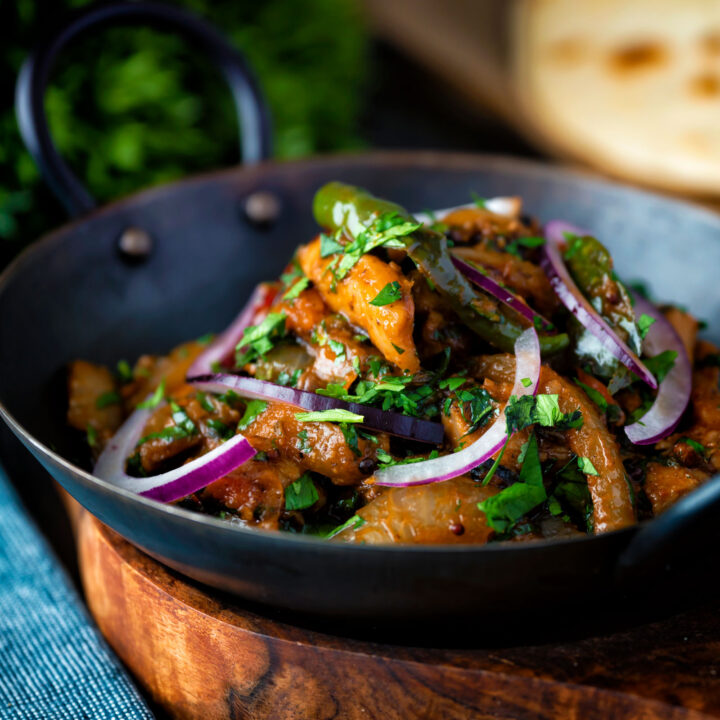 Achari chicken or murgh aka chicken pickle garnished with coriander and red onion.