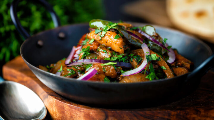 Achari chicken or murgh aka chicken pickle garnished with coriander and red onion.